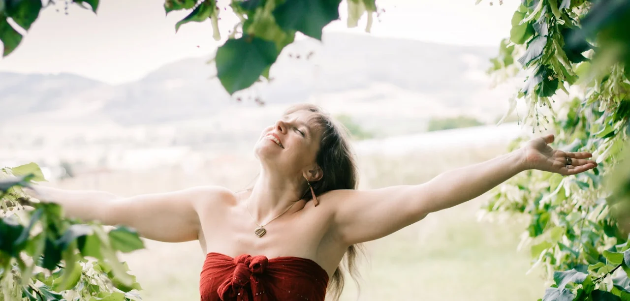 Lidwine dans la nature, bras ouverts vers le ciel